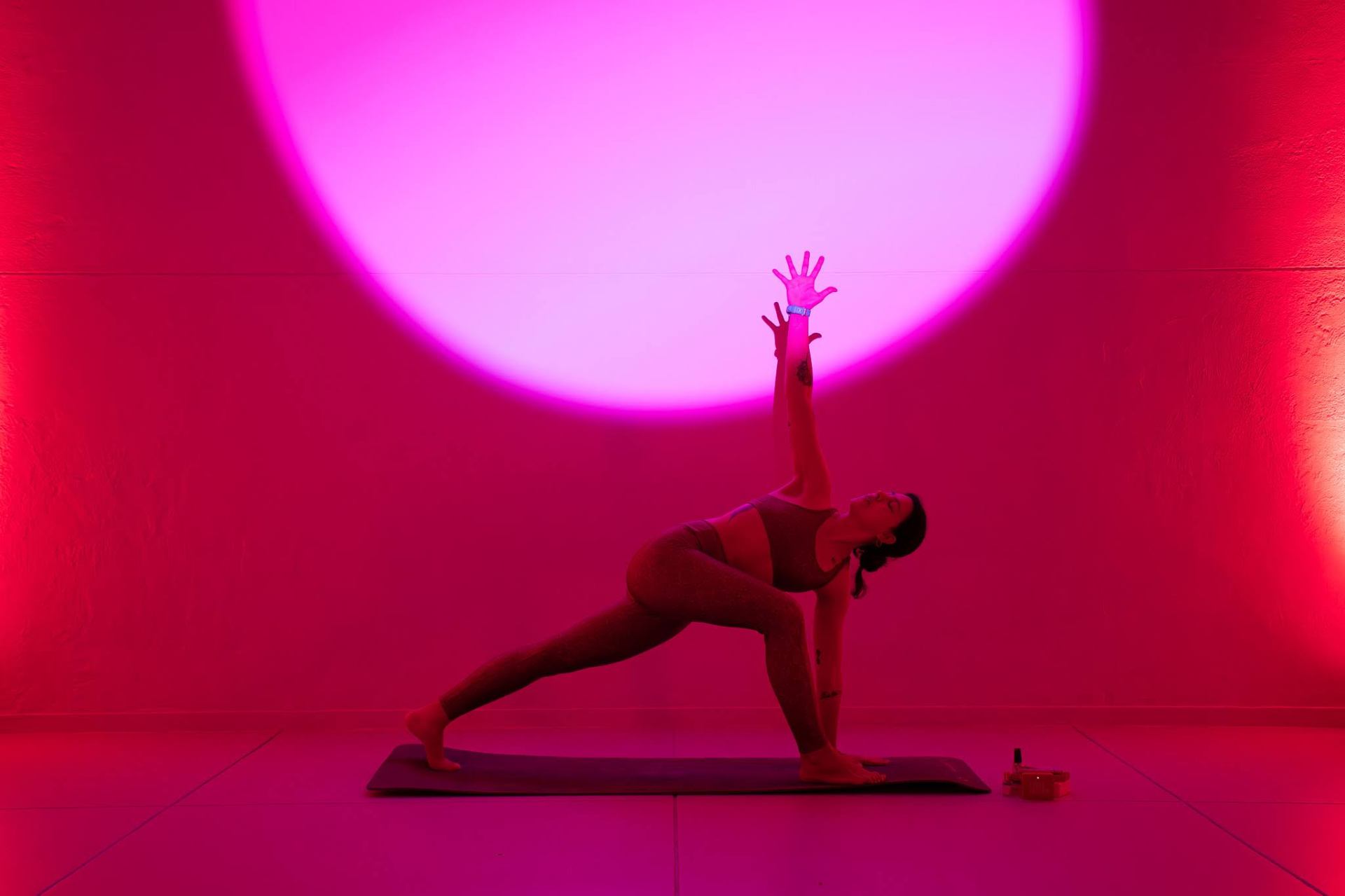Postura de yoga bajo luz rosa